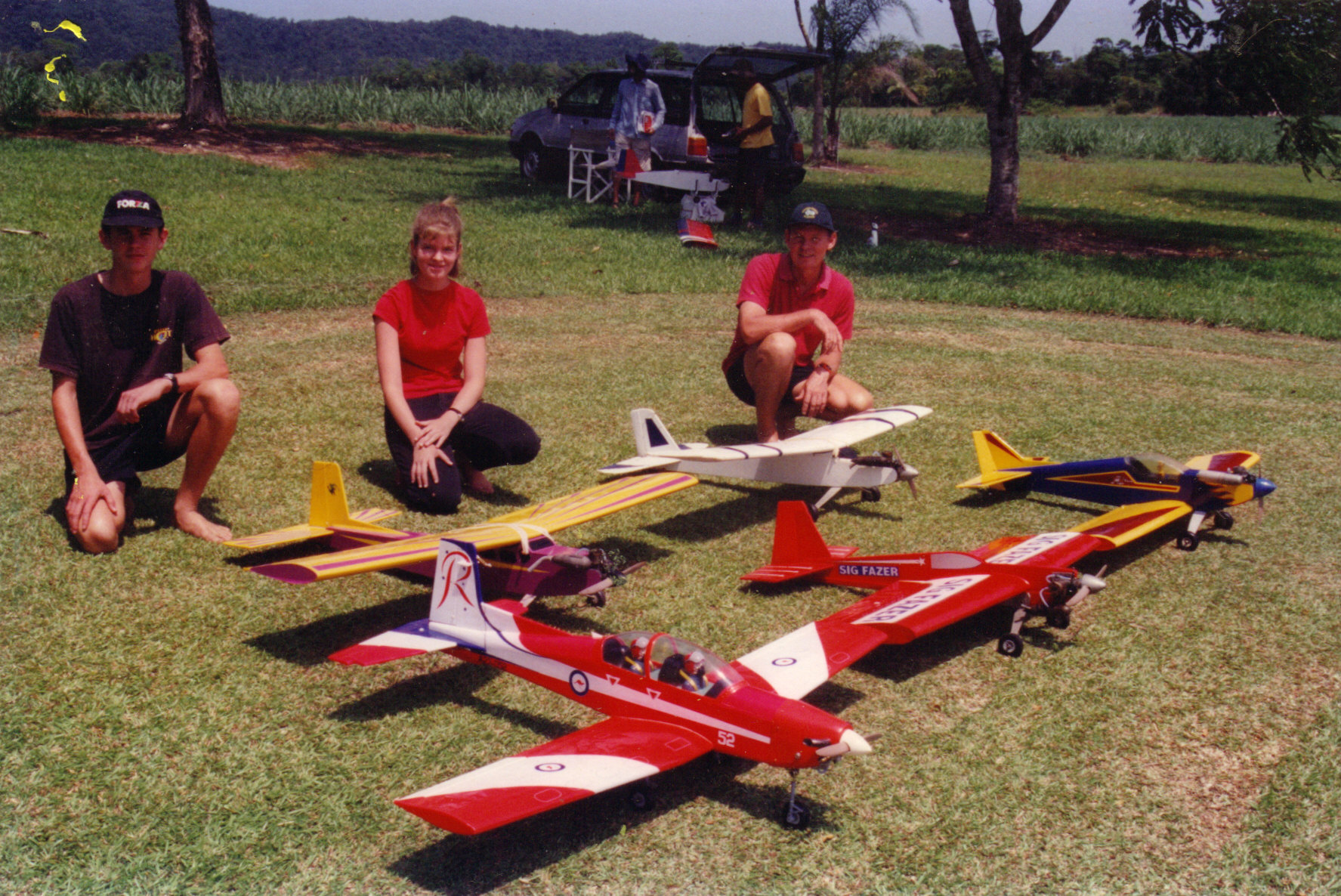 image: Melanie Olsen (middle) with her self-built remote-control plane (purple and yellow 40-60). Far North Queensland, 1997