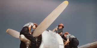 Three women working on the engine of an aeroplane